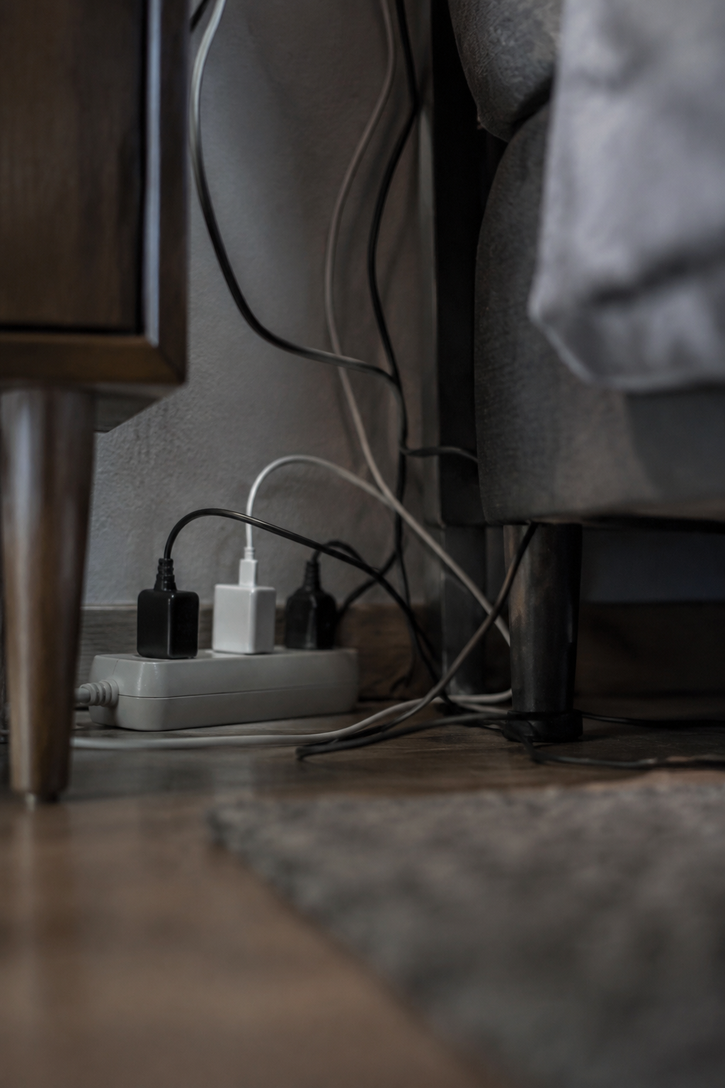 Cables enredados en un multitoma detrás de una mesa de noche
